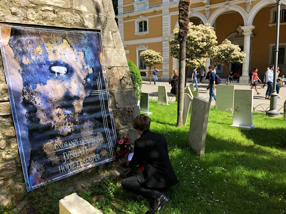 Carrara, il performer che “disturba” l'opera di Cattelan: il manifesto funebre di Rebor entra nell'installazione